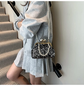 Détail du sac coquillage à paillettes noires avec grand fermoir perle et chaîne perlée