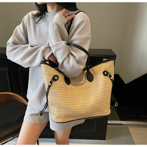Detail view of woven tote bag showing natural straw texture and black leather handles