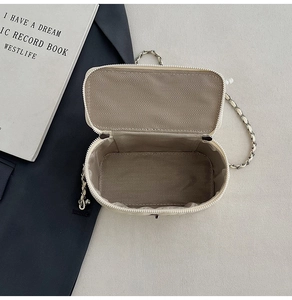 Detailed interior of beige quilted bag showing herringbone lining and metal chain strap