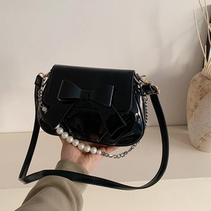 Glossy black bow shoulder bag with pearl handle and leather strap for spring 2025 fashion