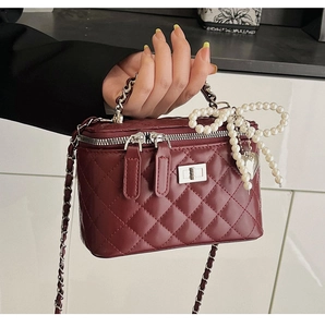 Detail of wine red quilted handbag with pearl bow and silver heart charm decoration