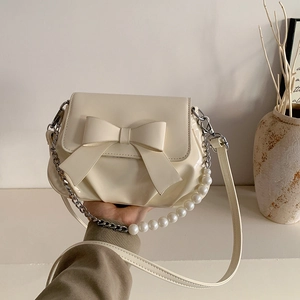 Chic cream bow shoulder bag with pearl strap and polished finish in a modern square shape