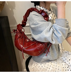 Détail du sac en cuir verni bordeaux avec bandoulière plissée et nœuds décoratifs