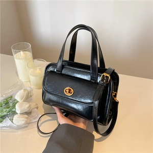 Classic black oil wax leather handbag with golden clasp shown in a lifestyle setting