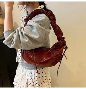 Détail de la bandoulière plissée bordeaux et du ruban latéral sur le sac sous l'aisselle