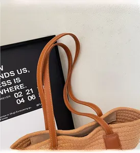 Détail du cabas en paille avec poignée en cuir marron et finitions surpiquées blanches