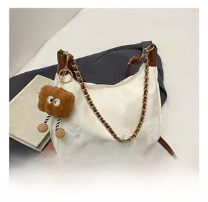 Detail showing the cream faux leather tote with brown trim and brown plush pendant