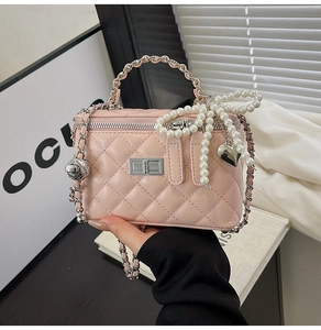 Detail of pink quilted handbag featuring pearl bow and silver heart pendant charm