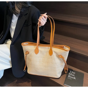 Detail of straw tote bag featuring contrast leather trim and side drawstring detail