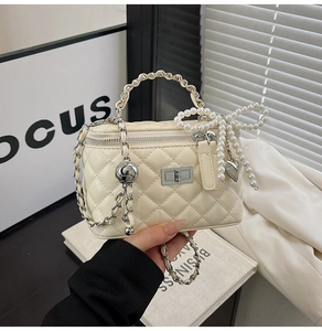 Detail of quilted beige crossbody bag with pearl bow and silver chain strap
