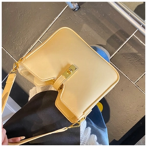 Detail of minimalist cream yellow shoulder bag featuring a gold metal twist lock closure