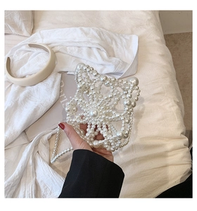 Detail of handmade white pearl handbag featuring star-shaped woven beads and chain strap