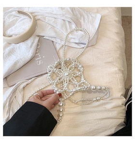 Detailed macro of handmade white pearl flower body chain on soft fabric background