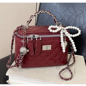 Close-up of wine red quilted crossbody bag with pearl bow and heart metal charms