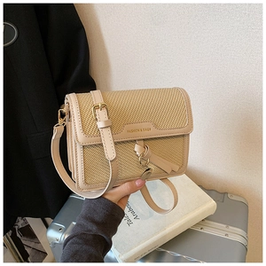 Close-up of beige woven texture and leather trim with gold logo on a retro shoulder bag