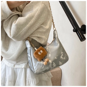 Close-up of metallic silver hobo bag with gold chain and cute plush toast charm pendant