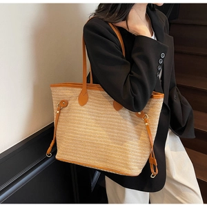 Detail of woven straw tote bag with brown leather handles and golden metal hardware