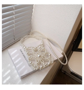 Macro detail of handmade pearl mesh handbag with flower pattern on a white book