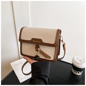 Detailed shot of retro crossbody square bag with beige straw texture and brown leather trim