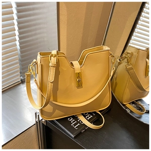 Detail of cream leather shoulder bag featuring a gold twist lock and a deep V-shaped top cut