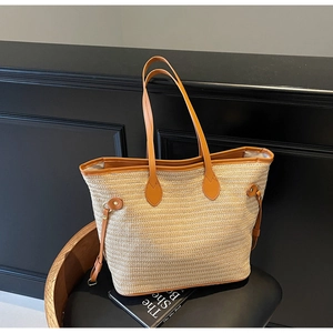 Detail of woven tote bag showing leather handles and side drawstring on wooden chair