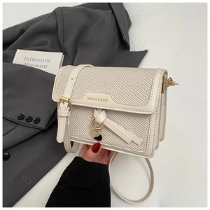 Close-up of cream woven square bag with metal ring charm and fashion engraving