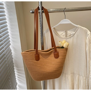 Detail of woven straw tote bag with brown leather handles and decorative white tulips