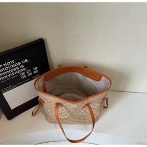 Close-up of beige woven tote bag with brown faux leather trim and interior zipper pocket