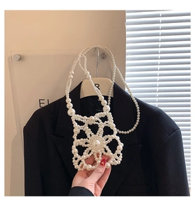 Detailed view of handmade pearl crossbody bag with hollow floral pattern and long strap