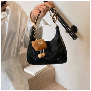 Detail of black glossy hobo bag with gold chain strap and brown plush cookie charm