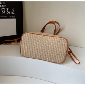 Detailed base view of a woven tote bag with orange leather trim and sturdy bottom