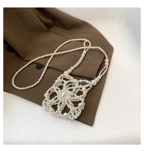 Detailed close-up of handmade white pearl woven crossbody bag on a textured background