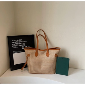 Detail view of beige woven tote bag with brown faux leather handles and metal hardware