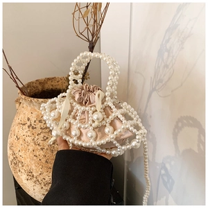 Detail of hand-woven pearl crossbody bag with champagne satin drawstring liner