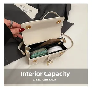 Detail view of the interior capacity showing smartphone and wallet in a cream flap bag