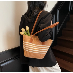 Gros plan d'un sac cabas tissé avec rayures blanches sur texture paille pour l'été