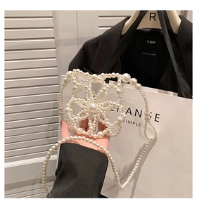 Detail of white pearl woven bag showing flower pattern and long chain strap