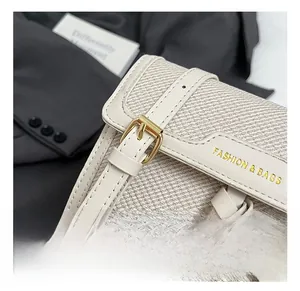 Detail of adjustable leather shoulder strap and woven texture on white shoulder bag