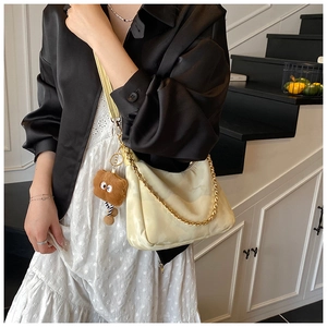Detail of cream PU leather tote bag with gold chain strap and brown plush charm