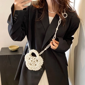 Detail of hand-woven white pearl crossbody bag featuring a round flower bud shape