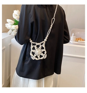 Detail view of handmade hollow flower pearl crossbody bag on a model wearing black blazer