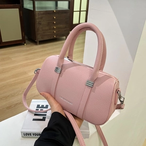 Pink cylinder handbag with lychee texture and silver hardware being held by hand