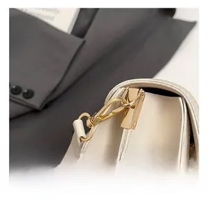 Detail shot of the golden metal hook and clean stitching on a cream leather bag