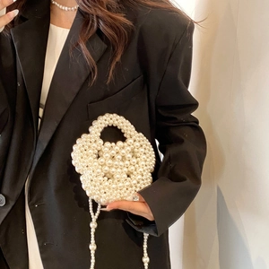 Detail of hand-woven white pearl crossbody bag featuring artistic petal-shaped profile