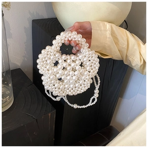 Detail of white handmade pearl beaded flower handbag with woven handle and chain