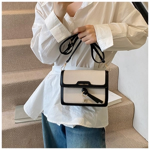 Detail of woven square crossbody bag with contrast trim on white shirt and denim