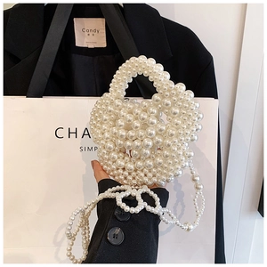 Detail of a handmade white pearl heart-shaped handbag with woven shoulder chain strap