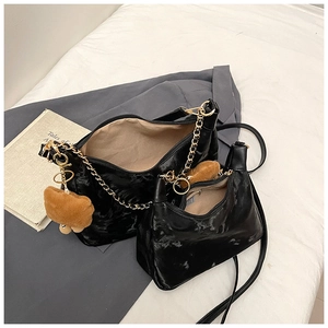 Detail of black glossy leather tote set with gold chain strap and cute bear charm