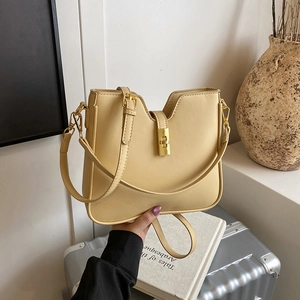 Minimalist cream shoulder bag with golden lock closure and sleek V-cut design