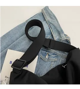 Detail of adjustable wide shoulder strap and durable plastic buckle on a black nylon bag